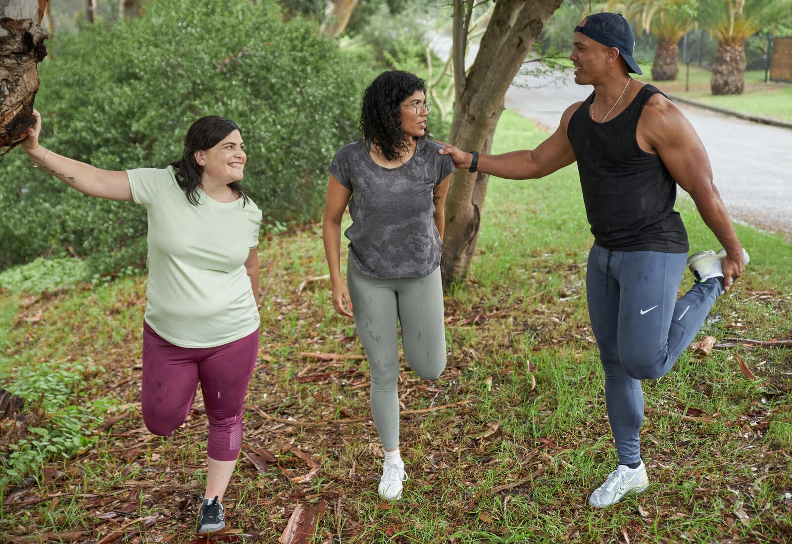 Three adults stretching together outdoors
